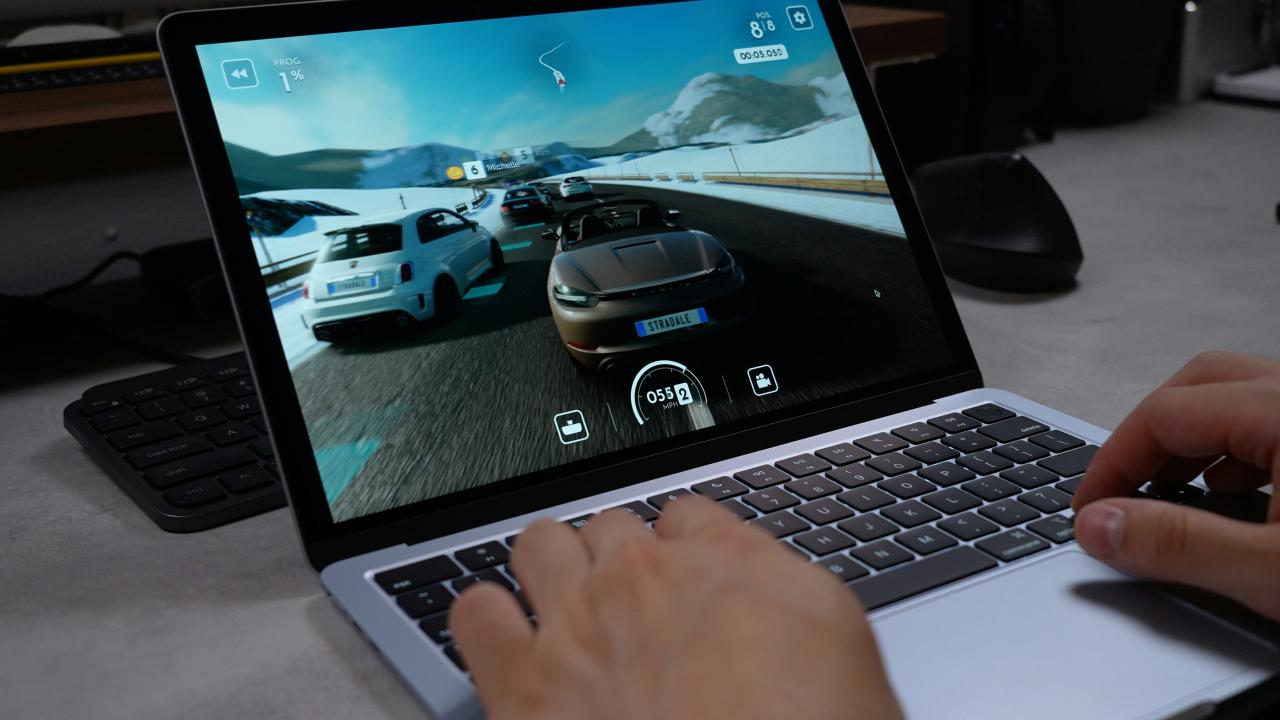 Person playing a racing game on a laptop.