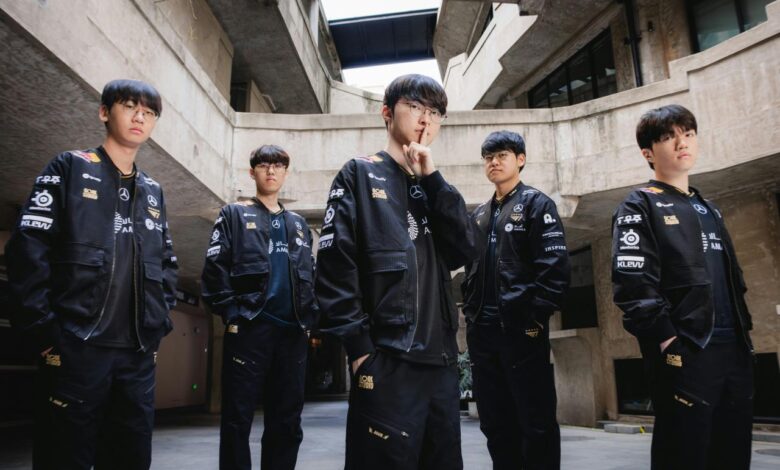 Five young men in matching black jackets stand together.