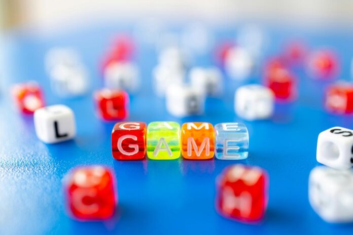The word GAME spelled out with colorful plastic letter cubes on a blue surface